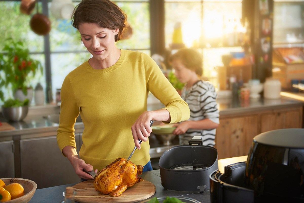 Philips Airfryer XL Black Friday Amazon: Frau kocht mit HeiÃŸluftfritteuse ein Huhn.