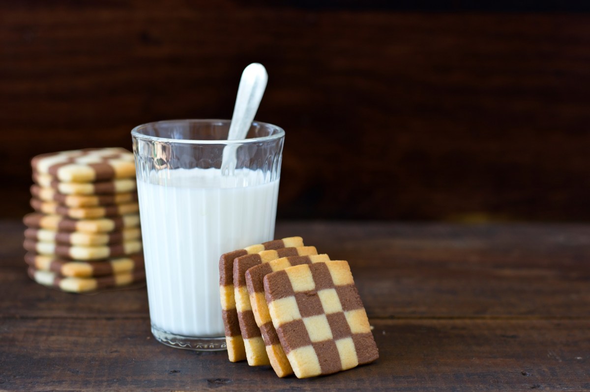 Schwarz-WeiÃŸ-GebÃ¤ck, das an einem Glas Milch lehnt.