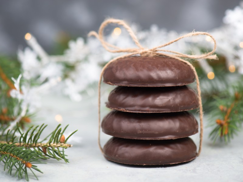 Rezept fÃ¼r Lebkuchen: 4 NÃ¼rnberger Lebkuchen gestapelt und mit einem Band zusammengebunden, dahinter Weihnachtsdeko.