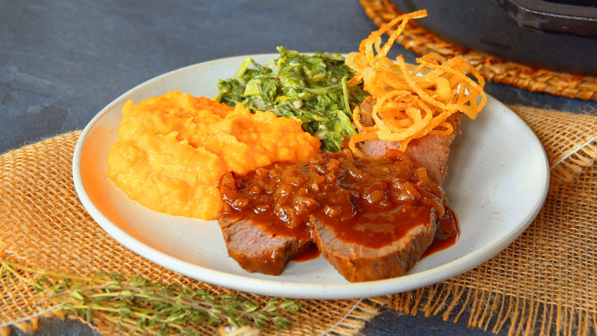 Zwiebelrostbraten mit KÃ¼rbispÃ¼ree und RÃ¶stzwiebeln auf einem Teller.