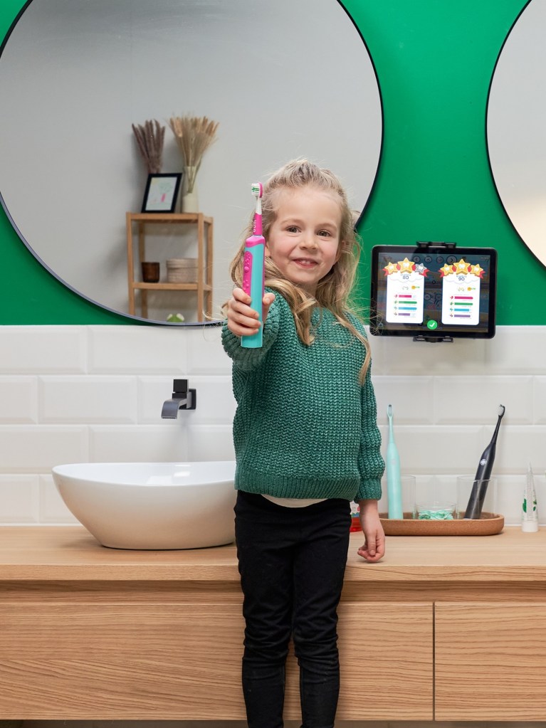 Adventskalender GUM Gewinnspiel: ein Kind hält eine elektrische Zahnbürste in der Hand und steht in einem Badezimmer.