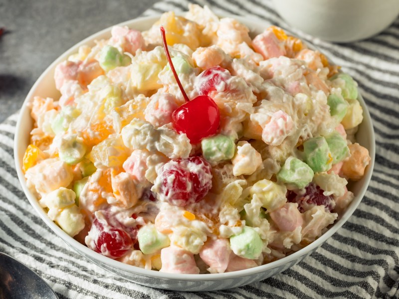 Ambrosia Salad in einer Schale, garniert mit einer Maraschino-Kirsche.