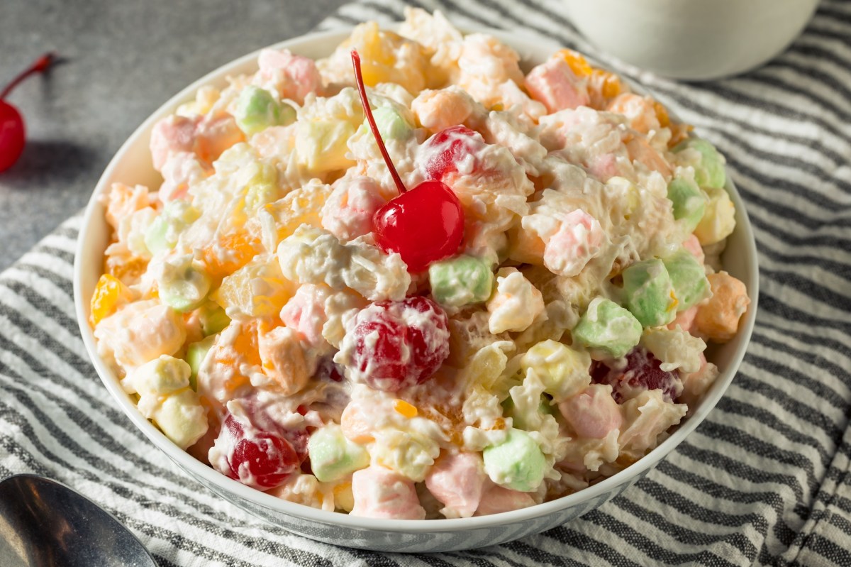 Ambrosia Salad in einer Schale, garniert mit einer Maraschino-Kirsche.