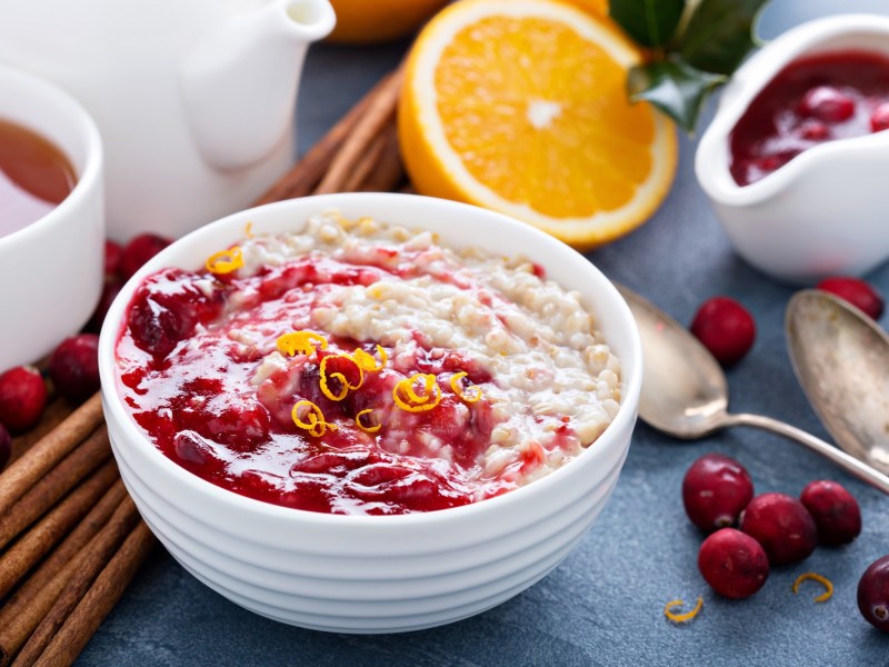 Eine SchÃ¼ssel Cranberry-Porridge mit etwas Orange.