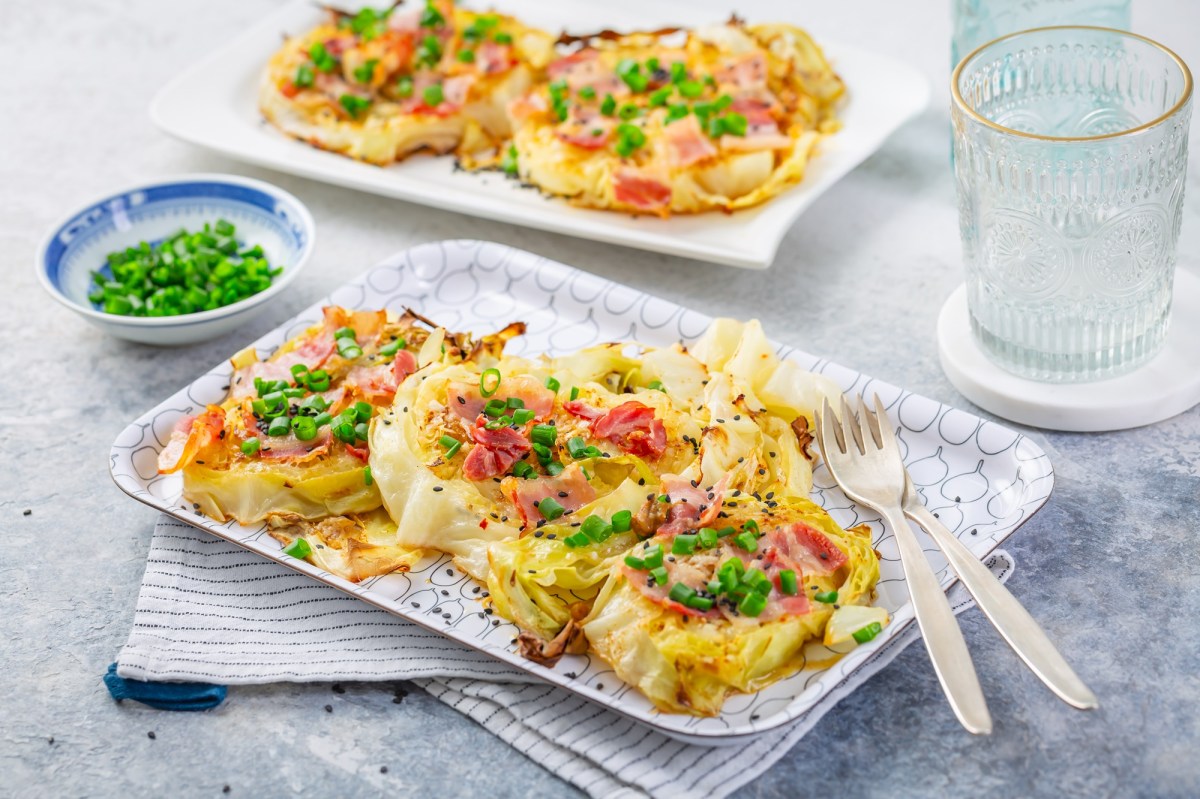 Zwei Servierplatten mit gebackenem WeiÃŸkohl mit Parmesan und Speck auf einem Tisch