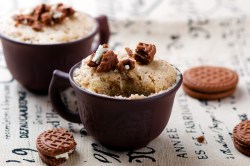 2 Tassen Lotus-Tassenkuchen garniert mit Kekskrümeln, drumherum einige Kekse.