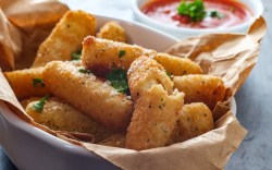 Mozzarella-Sticks aus der Heißluftfritteuse in einer Schale. Daneben ein Schälchen mit Ketchup.