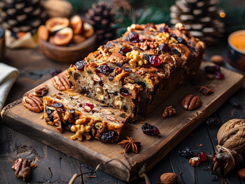 Nuss-Zimt-Kuchen auf einem Holzbrett, weihnachtliche Deko daneben