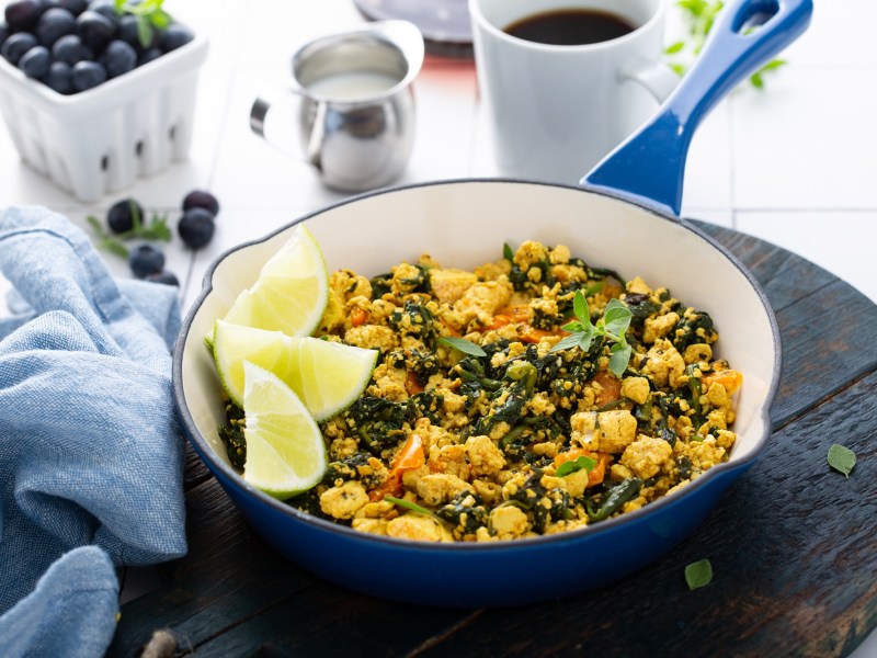 RÃ¼hrtofu in einer blauen Pfanne, garniert mit Zitrone.