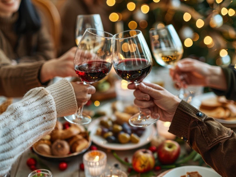 GemÃ¼tliche Runde stÃ¶ÃŸt beim Essen mit Wein an.