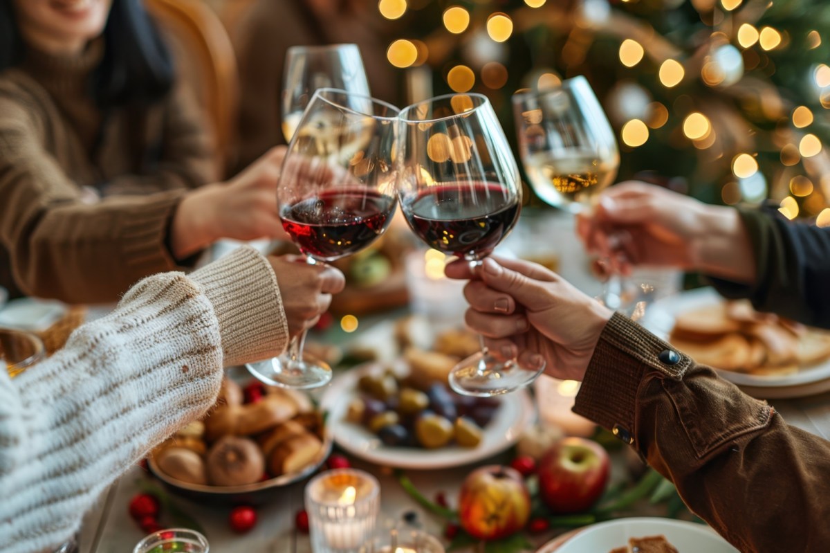 Gemütliche Runde stößt beim Essen mit Wein an.