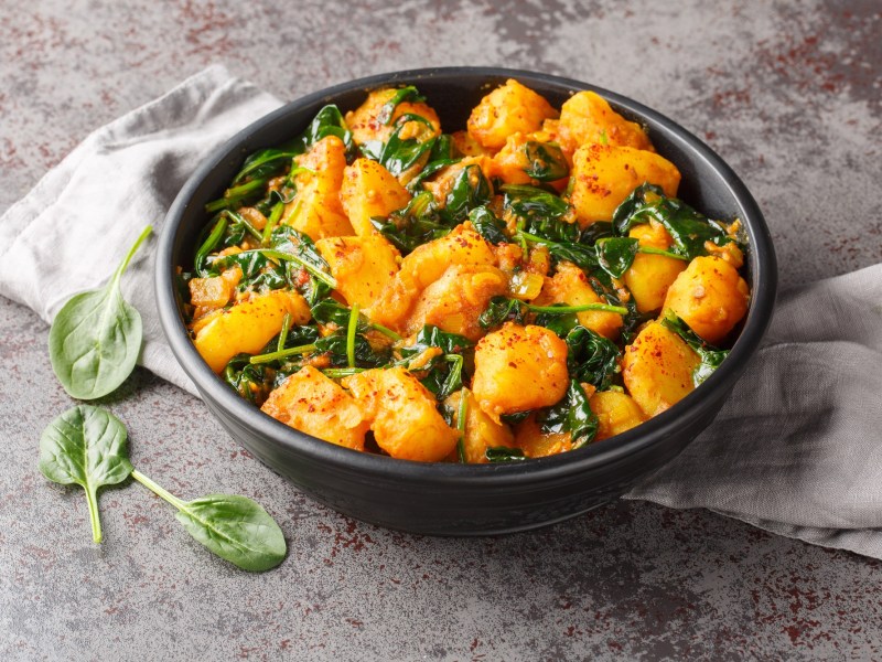 Aloo Palak: Kartoffel-Spinat-Curry in einer schwarzen Schale.