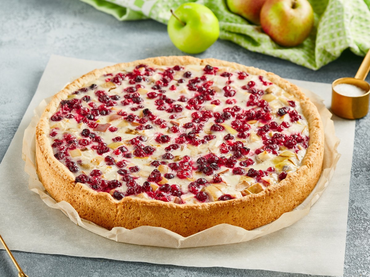 Ein ganzer Apfel-Cranberry-Kuchen auf einem Stück Backpapier.