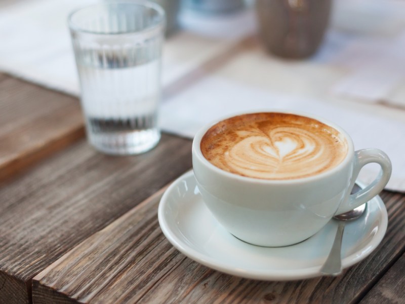 Ein Glas Wasser neben einer Tasse Kaffee auf einem Tisch.