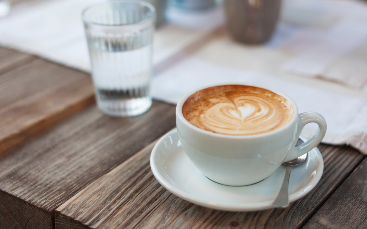 Ein Glas Wasser neben einer Tasse Kaffee auf einem Tisch.