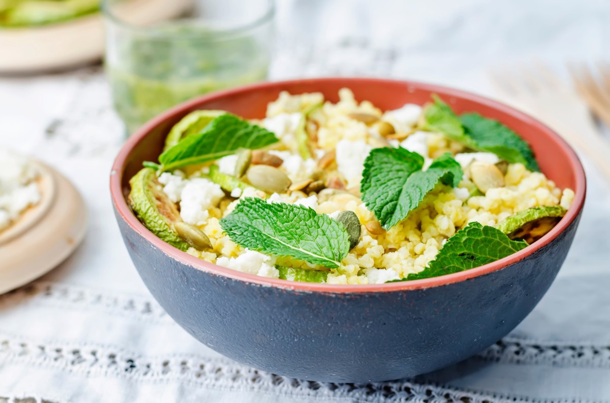 Hirsesalat mit ZiegenkÃ¤se in einer . Angerichtet mit frischen MinzblÃ¤ttern in einer schwarz-roten SchÃ¼ssel auf einem weiÃŸen Tuch.