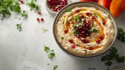 Schale mit Möhren-Frischkäse-Dip mit gehackten Pistazien und Granatapfelkernen on Top.