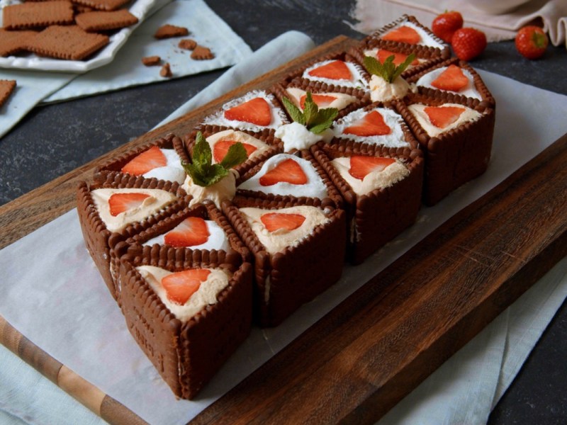 No-bake-Kuchen-mit-Butterkeksen, angerichtet auf einem Backpapier und Brett.