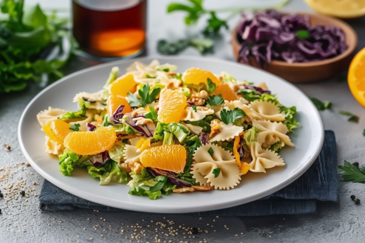 Ein Teller mit Nudelsalat mit Orangen und Chinakohl.