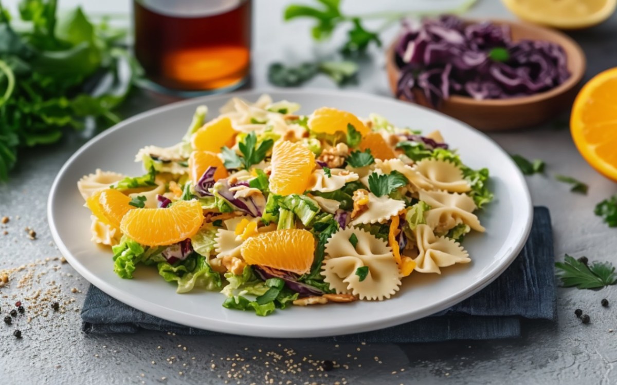 Ein Teller mit Nudelsalat mit Orangen und Chinakohl.