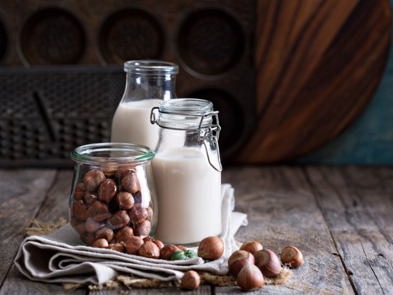 Nussmilch selbst machen: zwei Flaschen Haselnussmilch, davor HaselnÃ¼sse.