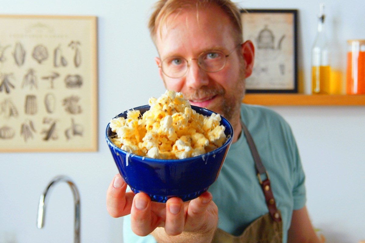 Ein Koch hält eine Schüssel Parmesan-Popcorn in die Kamera.