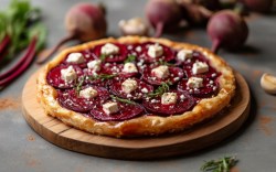 Eine vegane Rote-Bete-Tarte-Tatin auf einem runden Holzbrett.