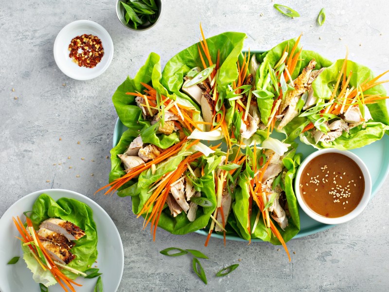 Ein groÃŸer Teller mit Salat-Wraps mit Huhn und einem Dip.