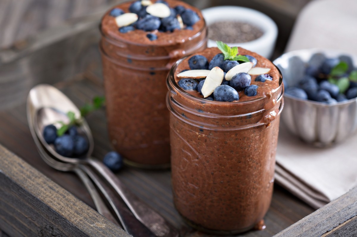 Zwei GlÃ¤ser Schoko-Chia-Pudding, garniert mit Beeren und Mandeln.