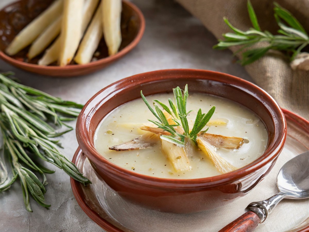 Schale mit Schwarzwurzel-Cremesuppe, Schwarzwurzeln und Kräuter daneben