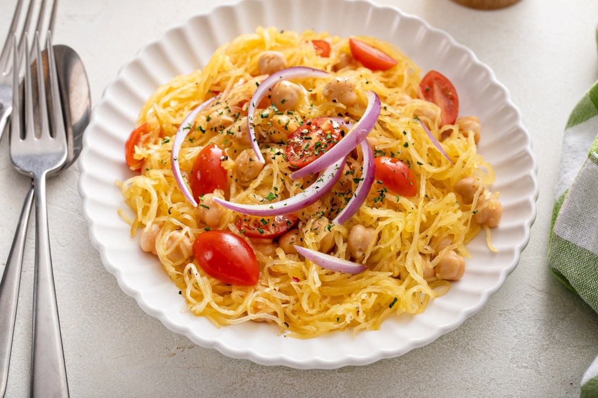 Ein Teller zubereiteter SpaghettikÃ¼rbis mit Tomaten und Kichererbsen.