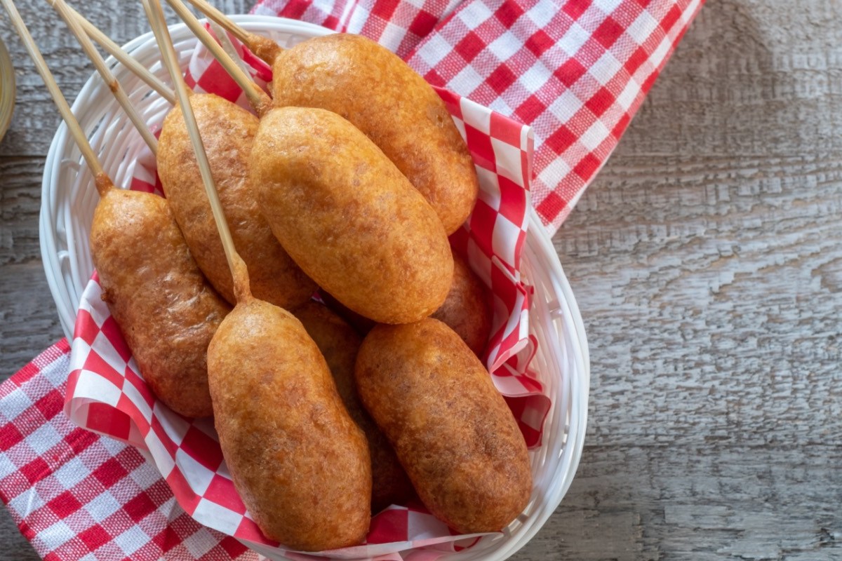 Mehrere vegane Corn Dogs in einem ovalen Korb. In der Draufsicht.