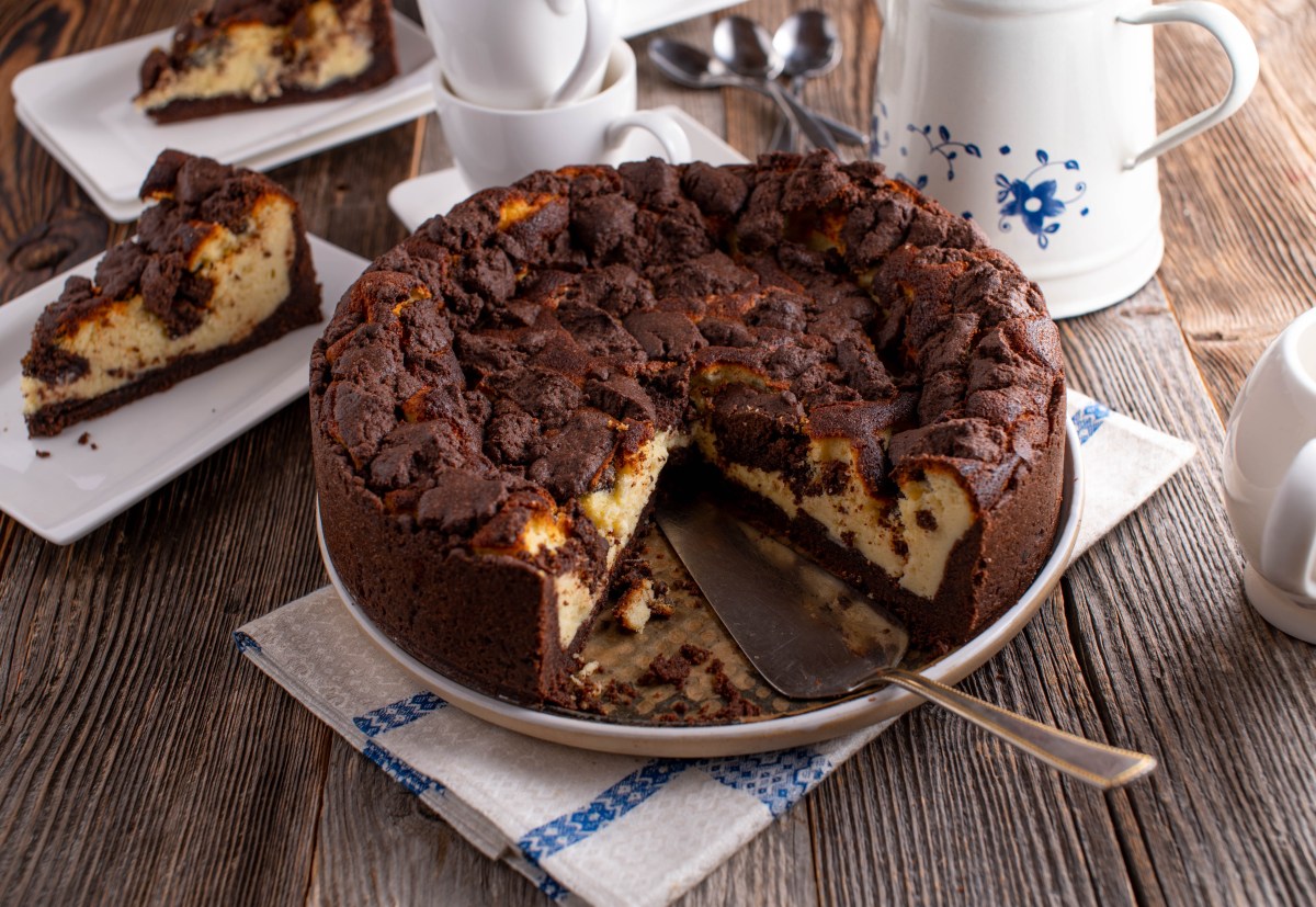 Ein veganer Zupfkuchen auf einem Kuchenteller, zwei StÃ¼cke wurde schon entnommen und liegen dahinter auf zwei Tellern.