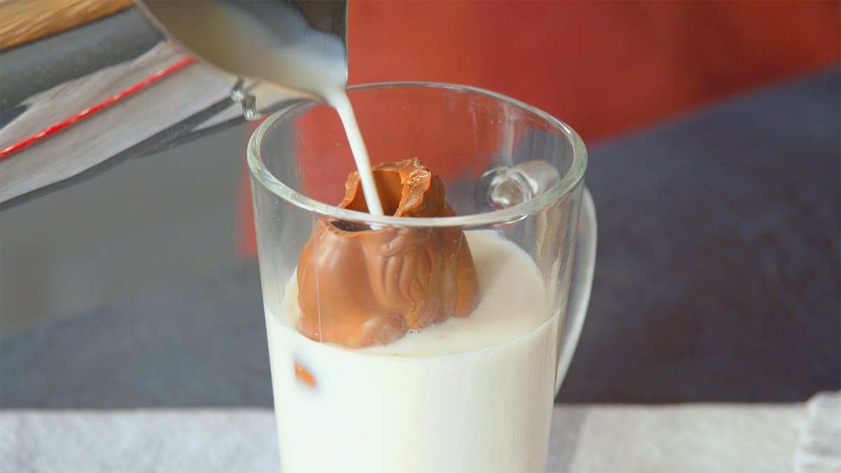 Weihnachtsschokolade aufbrauchen: Etwas Milch wird in einen angebissenen Schokoweihnachtsmann gefÃ¼llt.