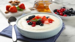 Eine Schüssel Grießbrei mit Eierlikör und Beeren, daneben ein Löffel und ein paar Zutaten.